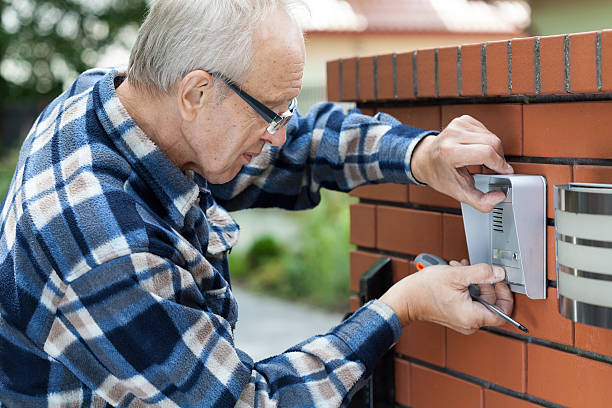 Technician repairing a gate intercom with a built-in camera for security