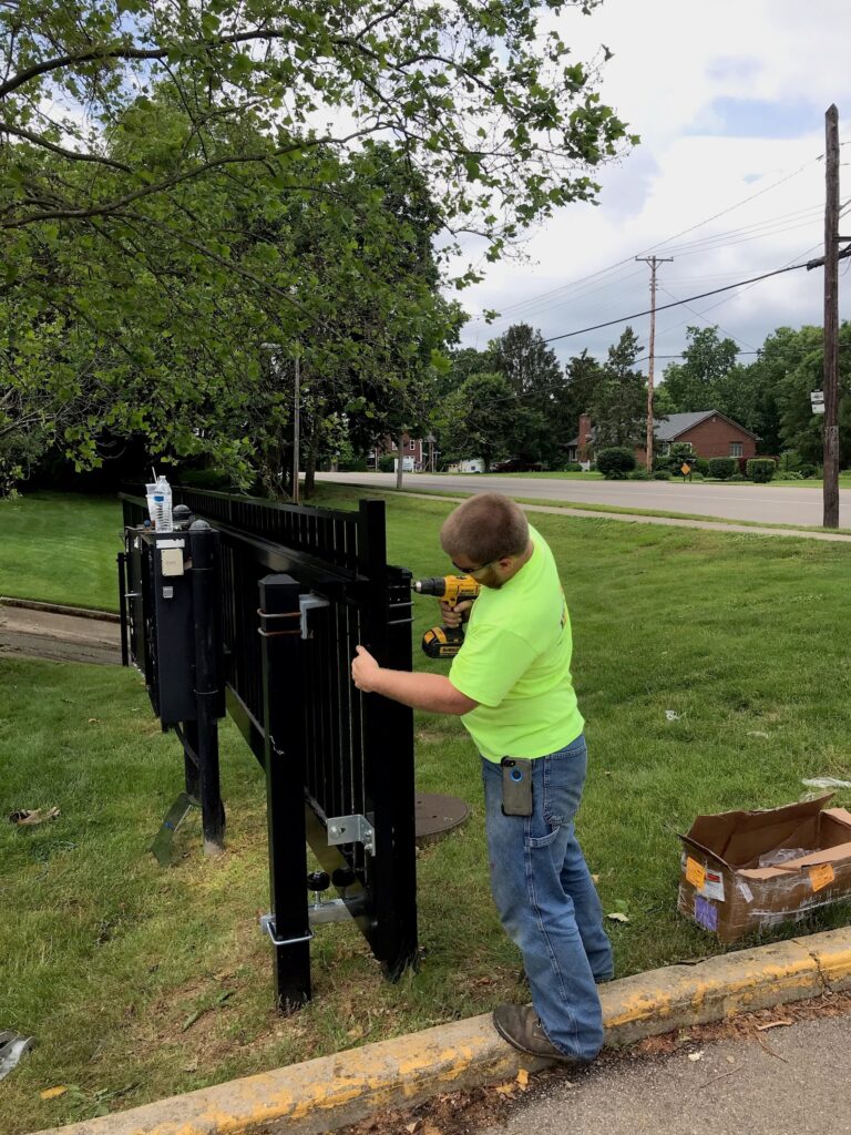 Technician installing an automatic sliding gate opener in a residential area