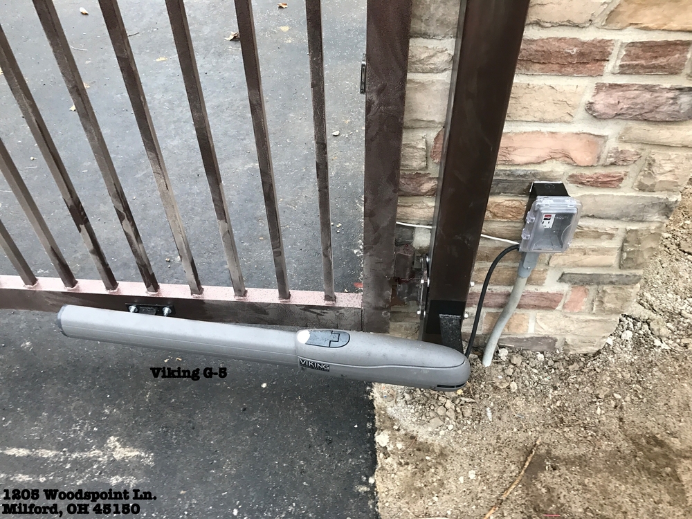 Electric arm actuator gate opener on black metal gate with welding