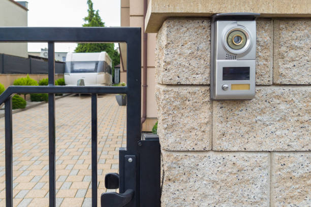 Gate video intercom mounted on a stone wall with a camera and speaker