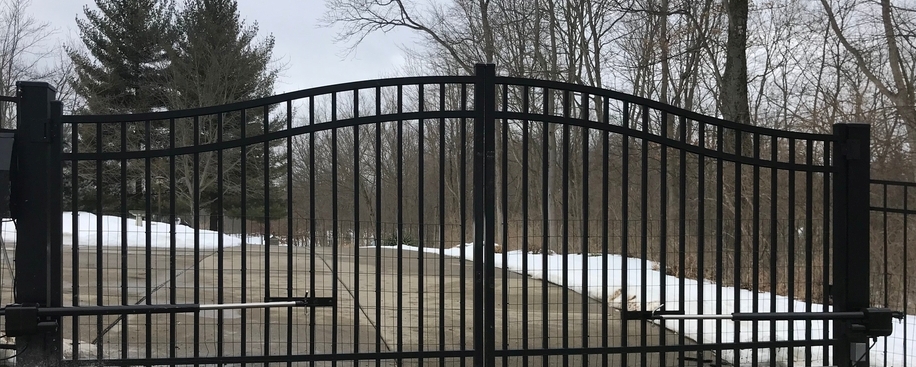 Automatic swing gate opener installed on a black iron driveway gate