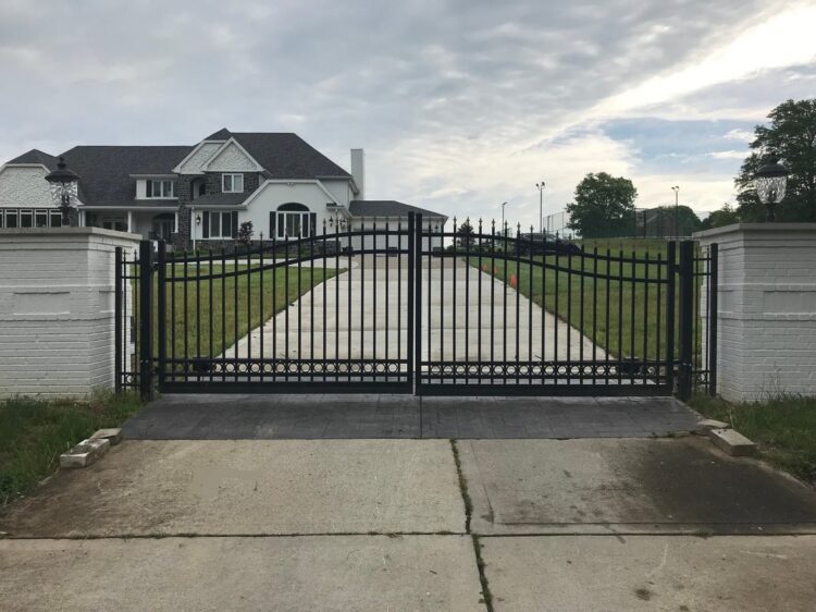 Modern residential gate with brick pillars and a paved driveway
